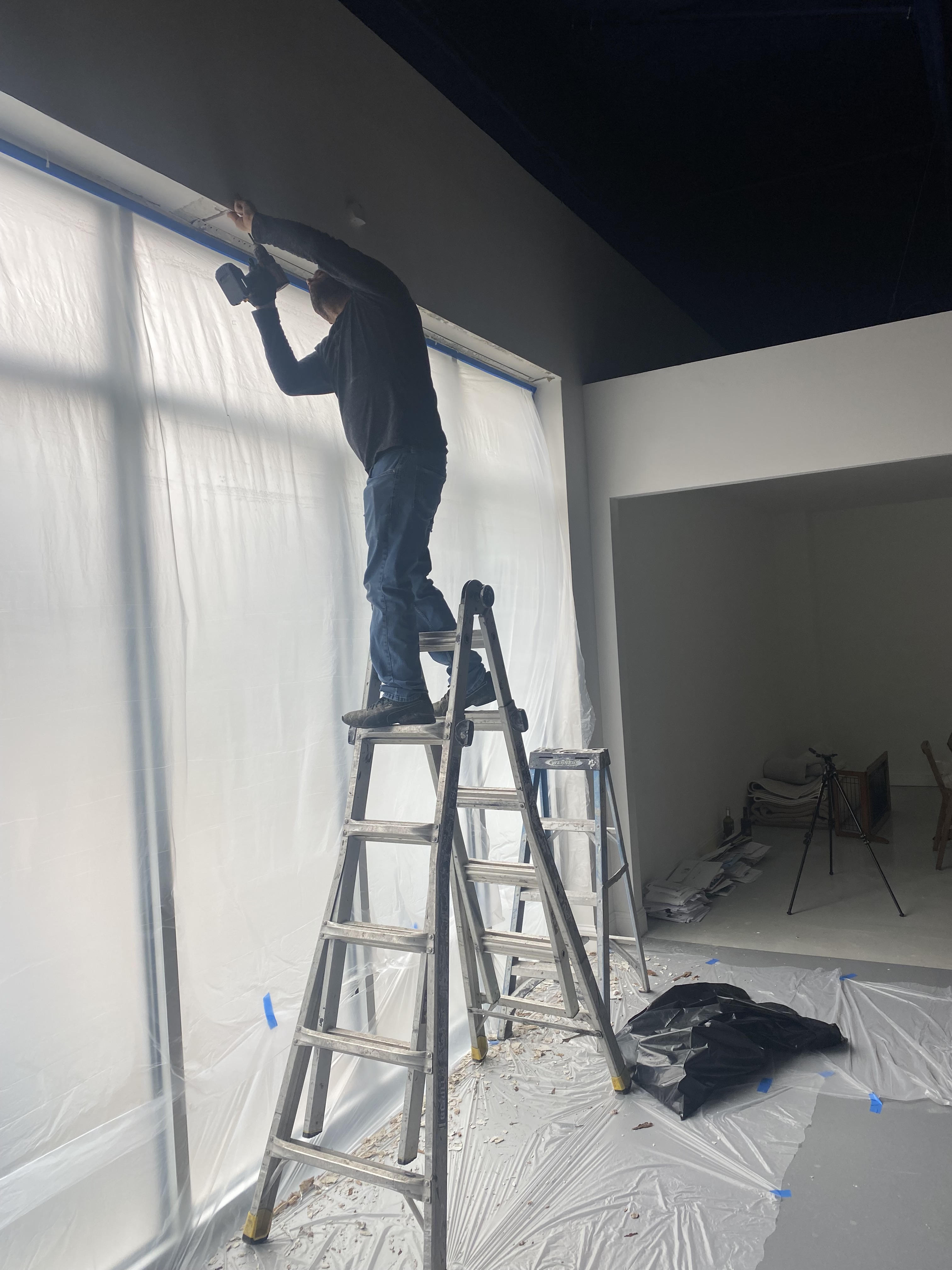 A clean and modern kitchen featuring white cabinets, island, and countertops, complemented by stainless appliances and lig...